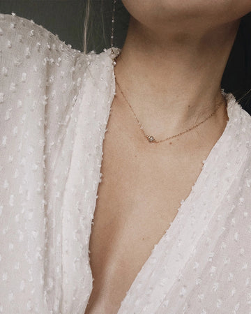 Memorial necklace with a small pendant worn by a person in a white textured garment.