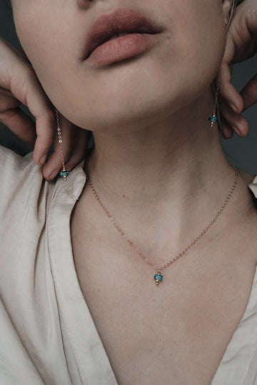 Close-up of a person wearing a delicate memorial necklace with a small pendant.