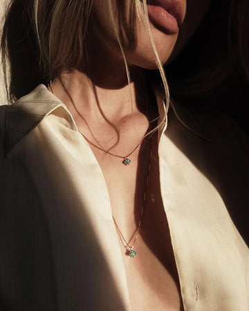 Close-up of a person wearing a delicate cremation necklace with a small pendant.
