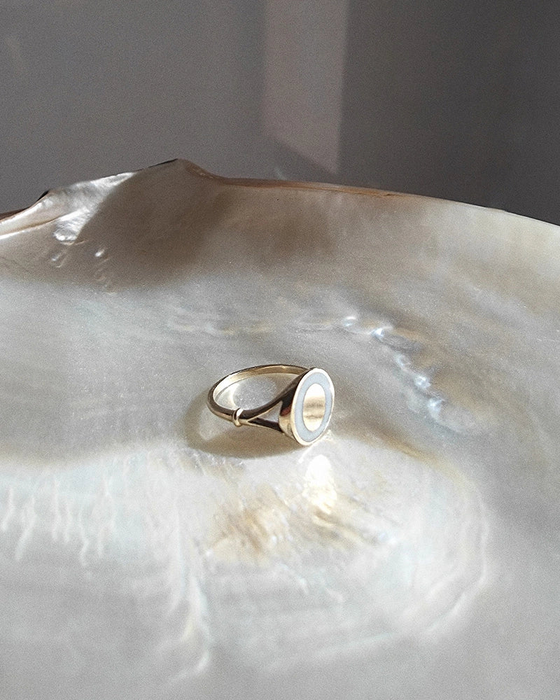 Gold memorial ring with a white gemstone on a large shell to remember a lost loved one.