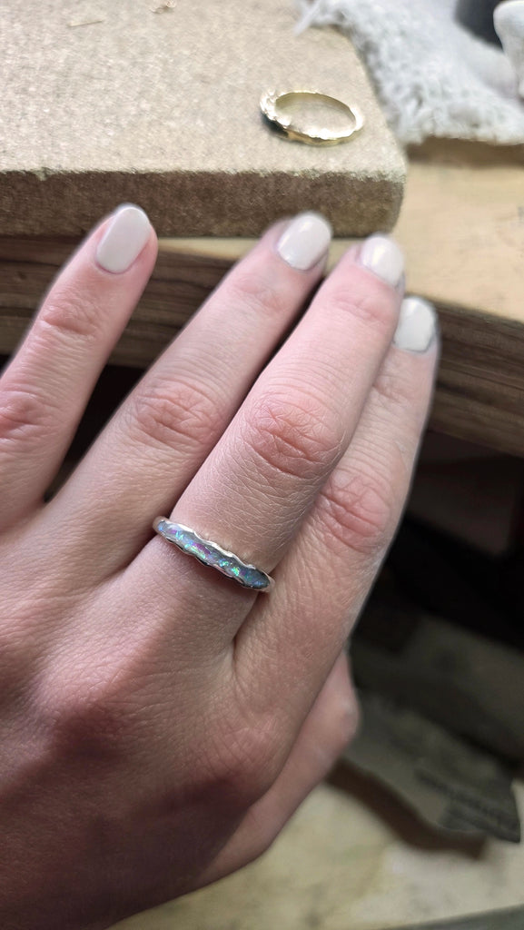 Hand wearing a silver remembrance ring with a blurred background.
