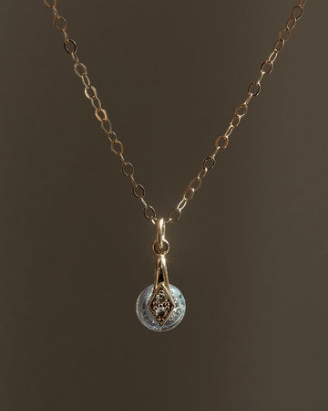 Gold memorial necklace with a cremation pendant on a dark background