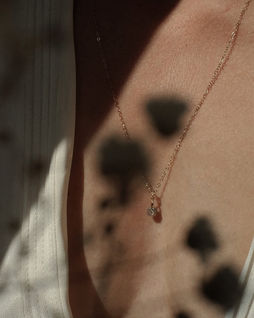 Cremation necklace with a small memorial pendant on a model