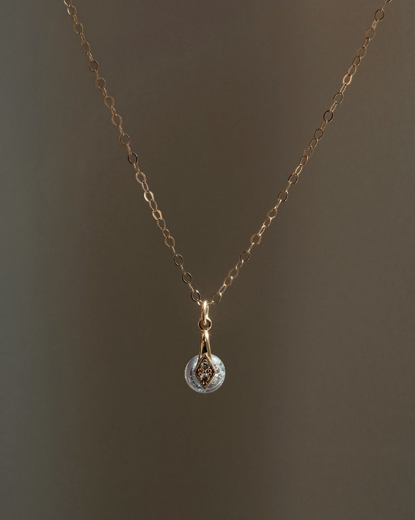 Gold necklace with ashes a teardrop memorial pendant on a dark background