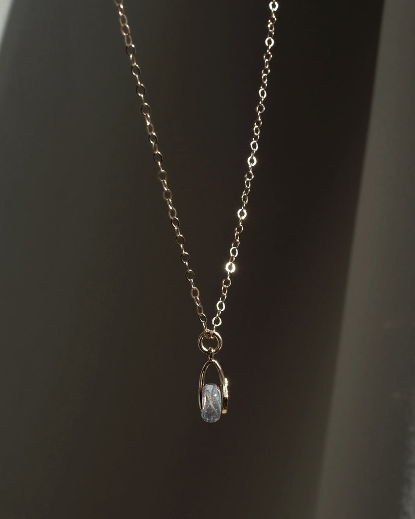 Memorial necklace with a pendant with ashes on a dark background