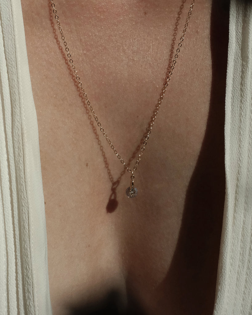 Gold keepsake necklace with a small keepsake pendant on a person's neck against a neutral background