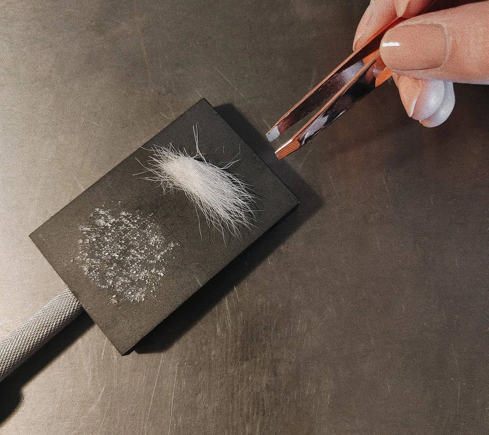 Person using tweezers to pick up a  fur or ashes to make memorial jewelry.