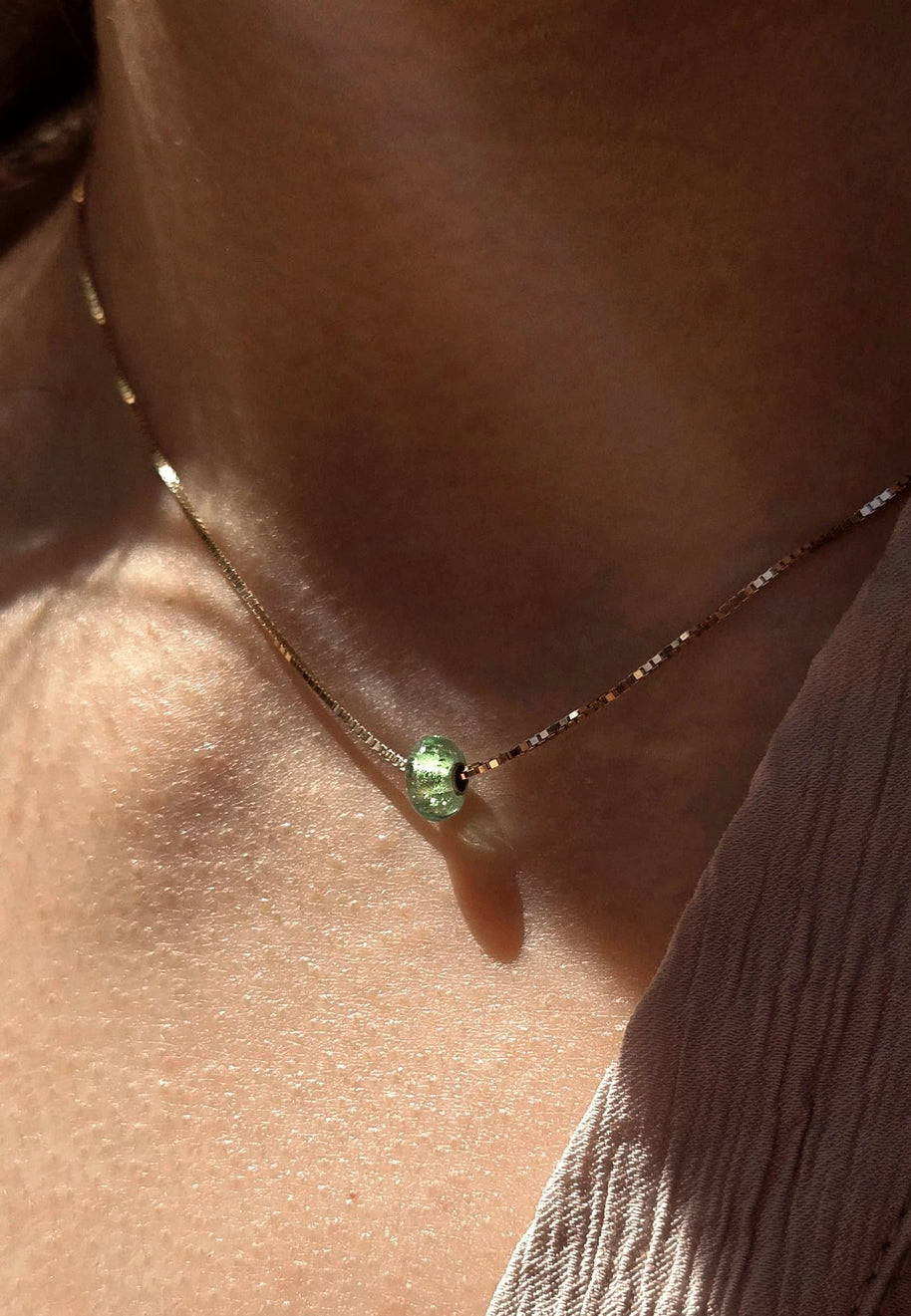 licht dat schijnt op asbedel aan een asketting gedragen door een vrouw