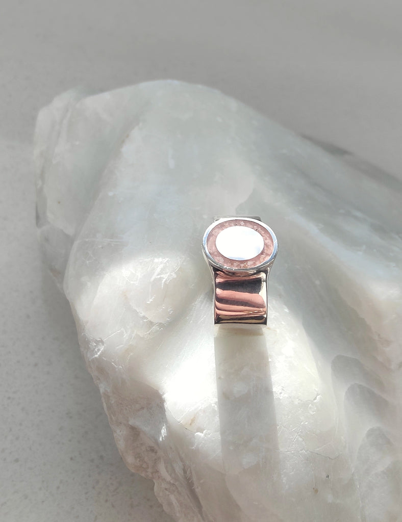 Silver ring with a white stone on a light gray background