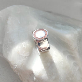 Silver ring with a pink stone on a white stone background