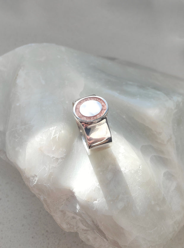 Silver ring with a pink stone on a white stone background