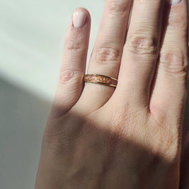 Hand wearing a gold cremationring with a neutral background.