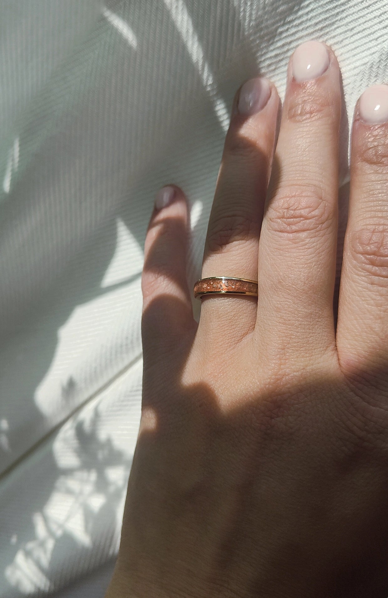 Hand wearing a cremation ring with a white background