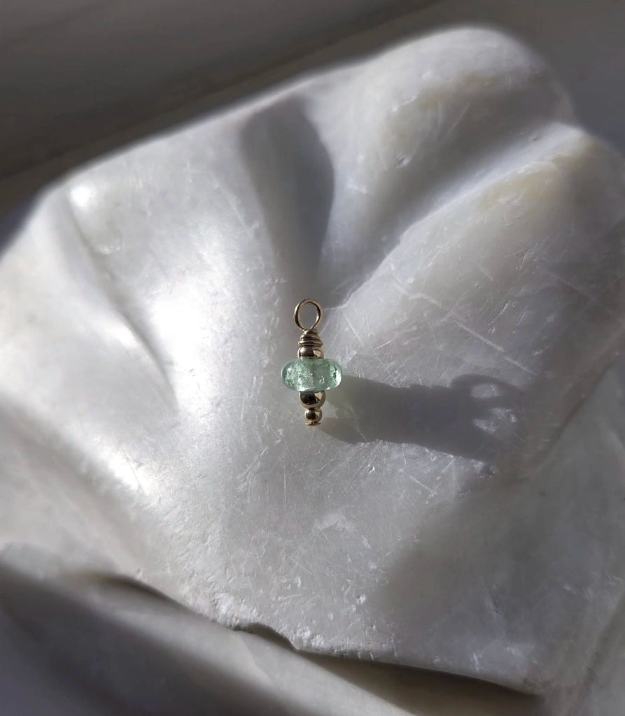 Small green gemstone cremation pendant on a white stone surface.