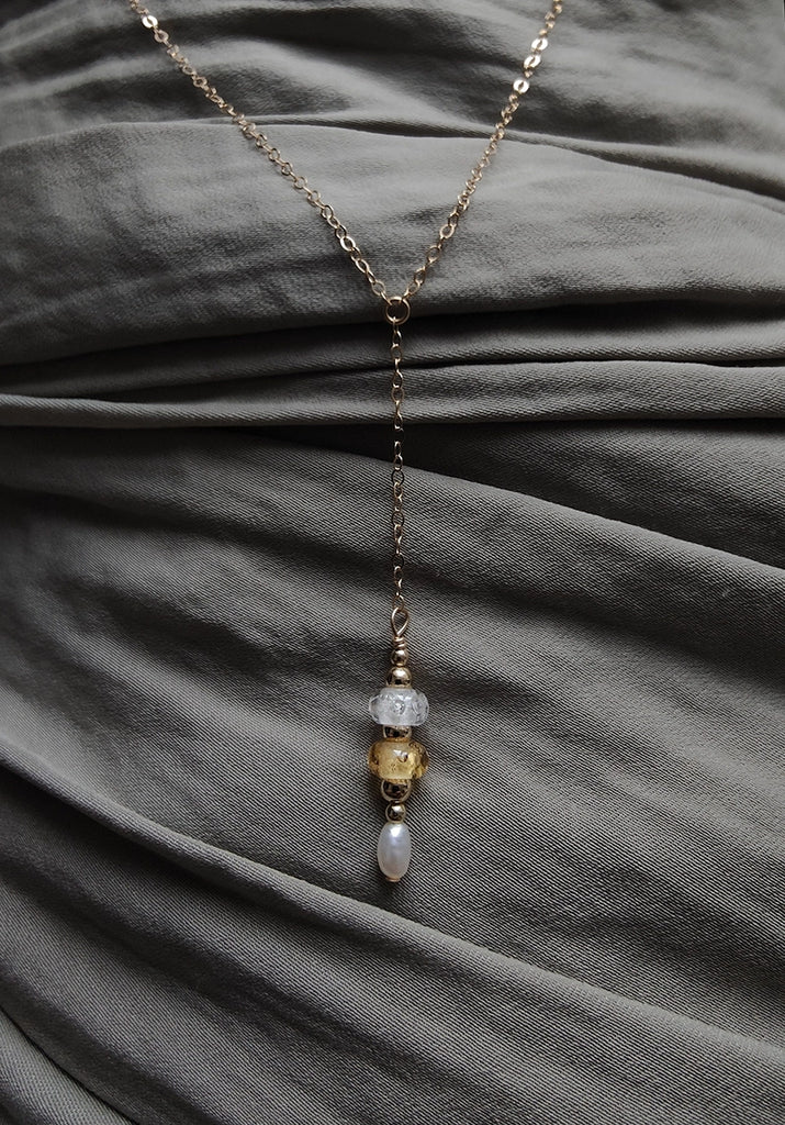 Delicate memorial necklace with beads on a gray fabric background.