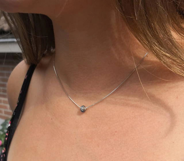 Close-up of a memorial necklace with a small pendant on a person's neck to remember her boyfriend.