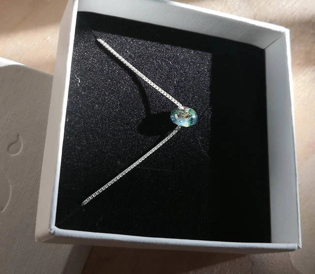 Memorial necklace with a green gemstone in a box.