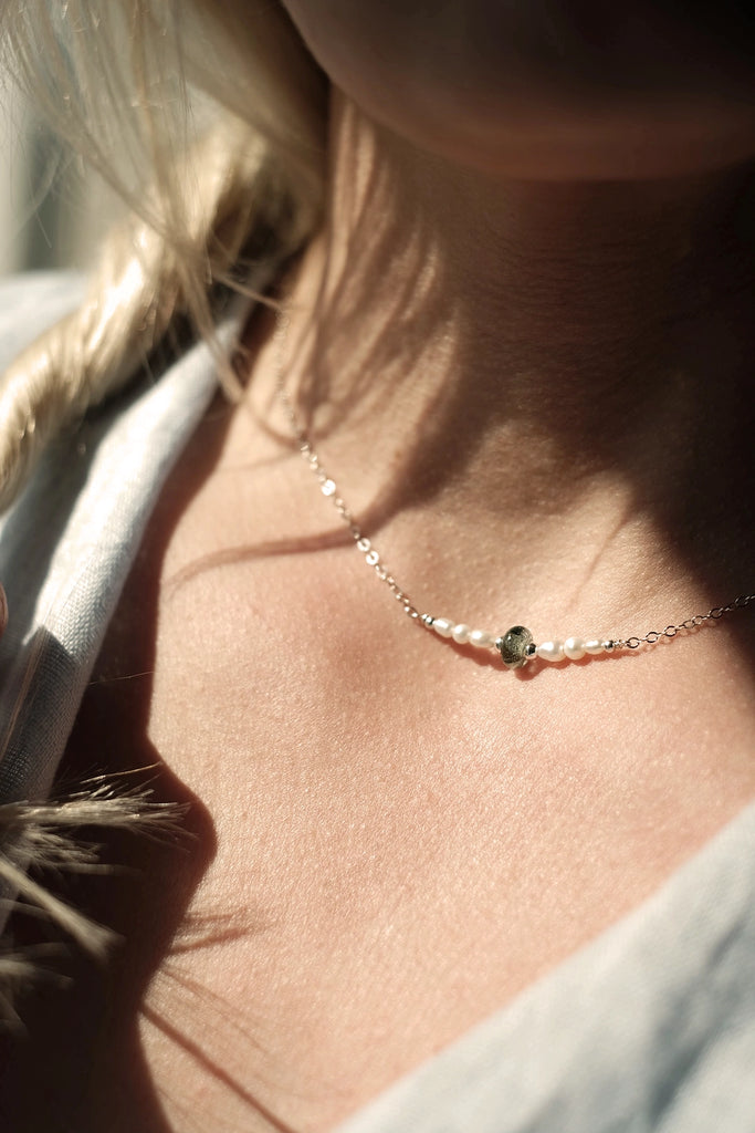 Close-up of a person wearing a delicate cremation necklace with a small pendant.