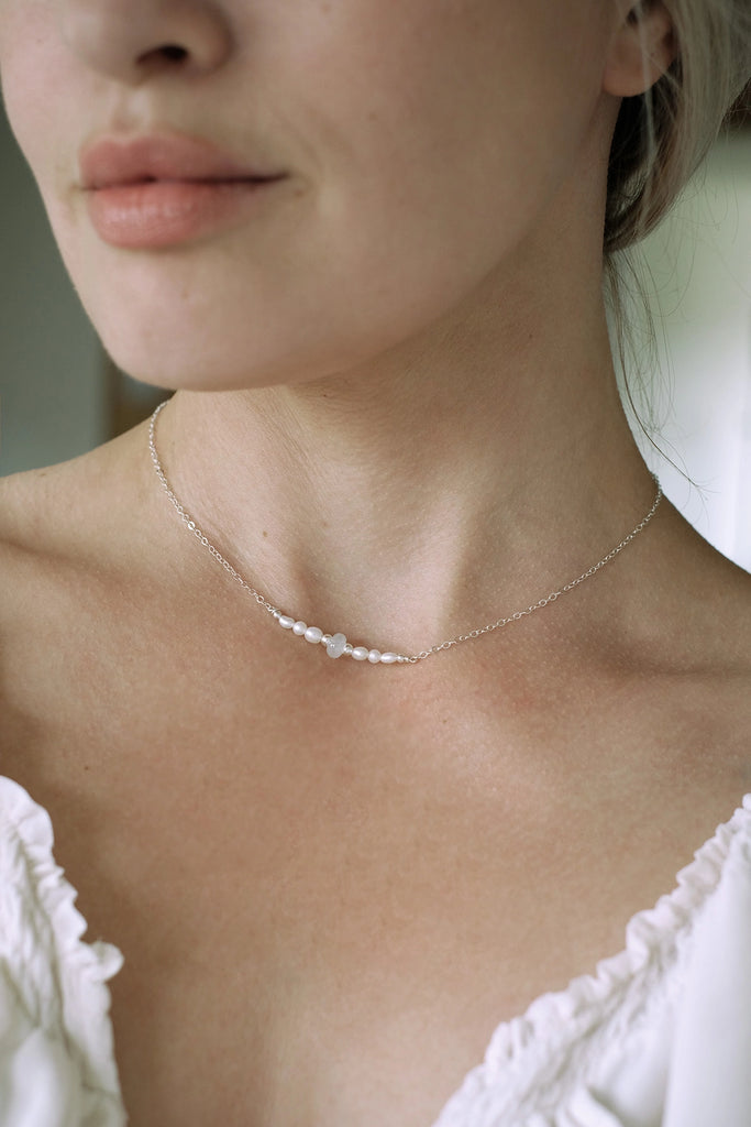 Close-up of a person wearing a delicate memorial necklace with a blurred background.